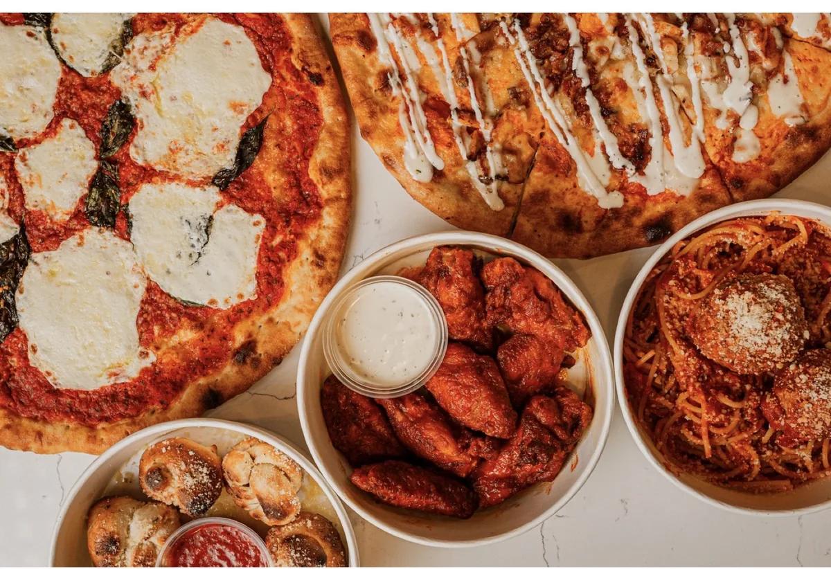Pizzas, wings, garlic knots and spaghetti on a marble table